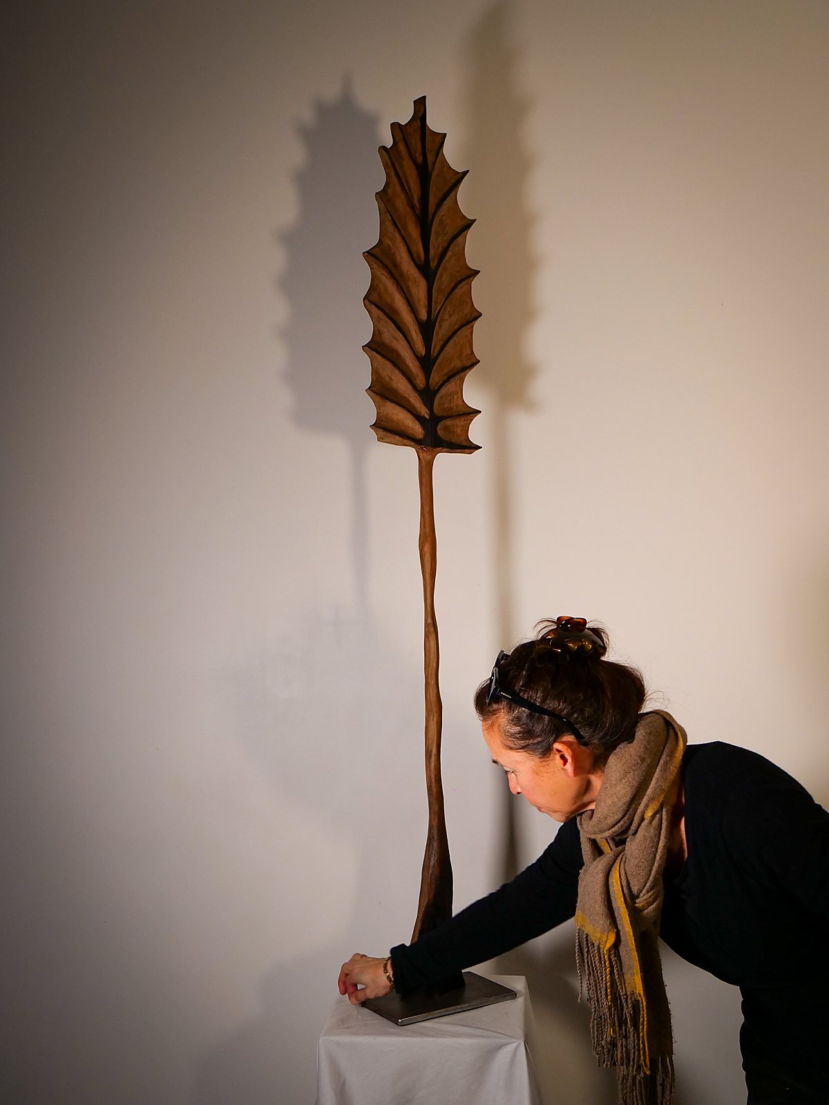 Florence Nguyen accrochant la sculpture Feuille au mur de l'atelier
